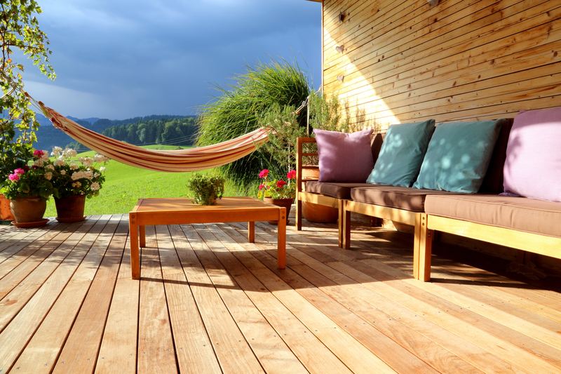 Holzterrasse mit Hängematte, Sitzbank und Blumentöpfen